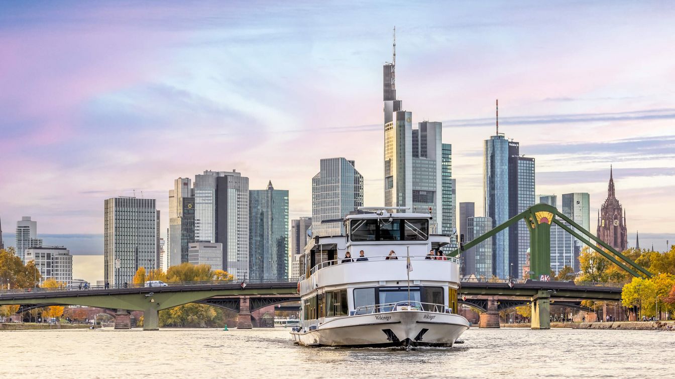 Schiff der Primus Linie in der Abenddämmerung auf dem Main mit der Frankfurter Skyline im Hintergrund.