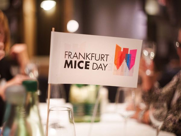 Ein Fähnchen mit dem Logo des Frankfurt MICE DAY steht auf einem eingedeckten Tisch.