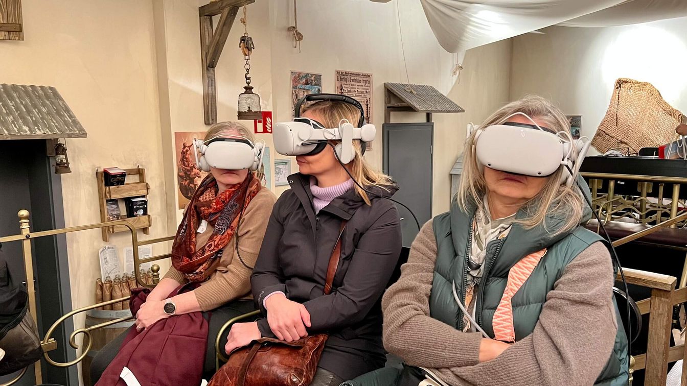 Drei Frauen mit VR-Brillen auf einer Kutsche.